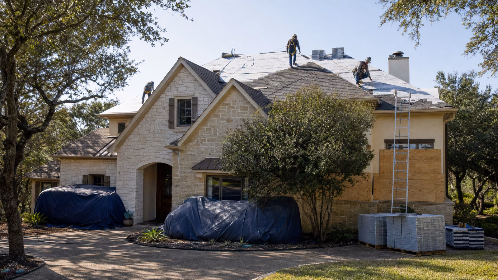 Roofing crew preparing a Central Texas limestone home for shingle replacement