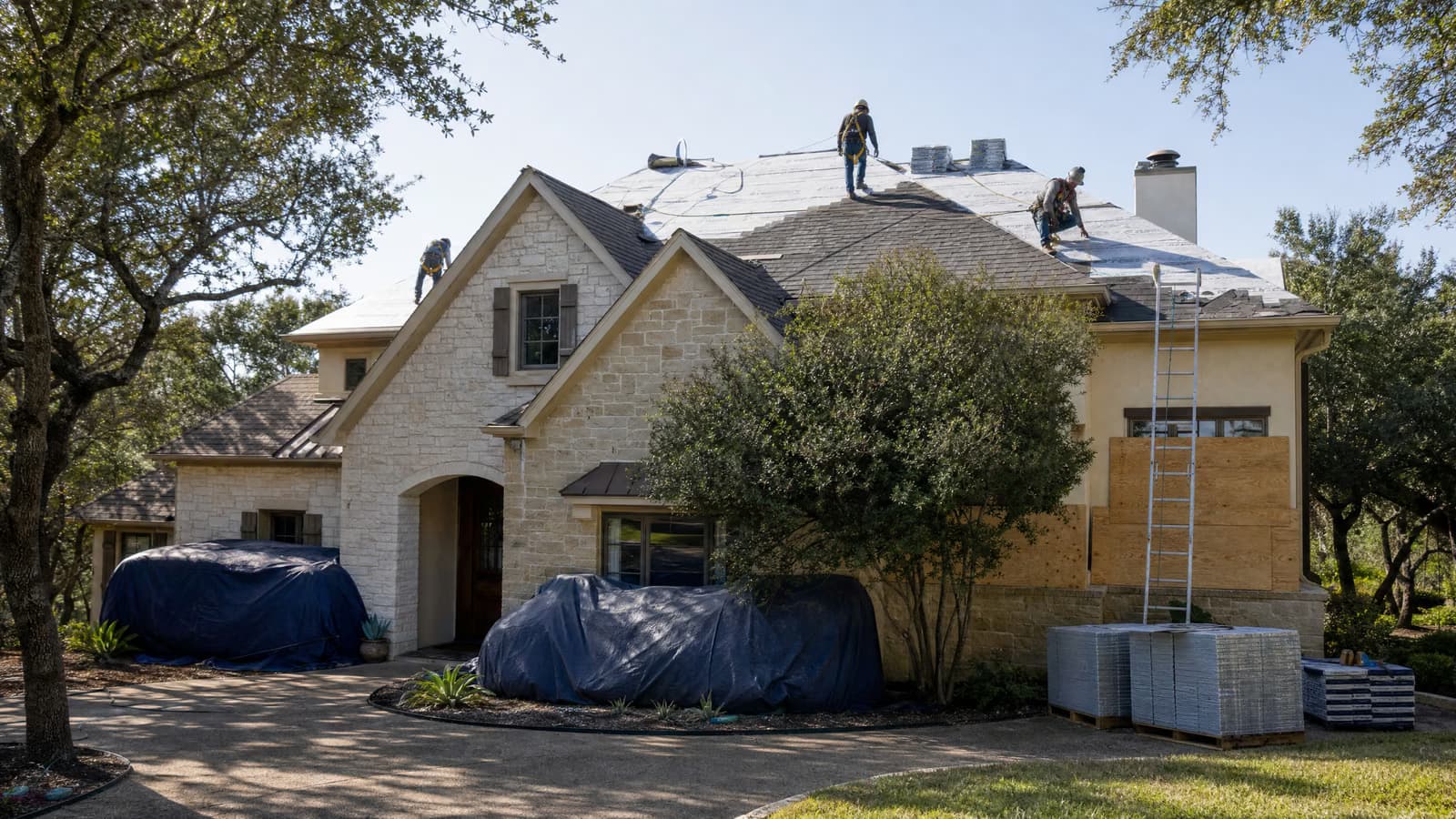 Roofing crew preparing a Central Texas limestone home for shingle replacement